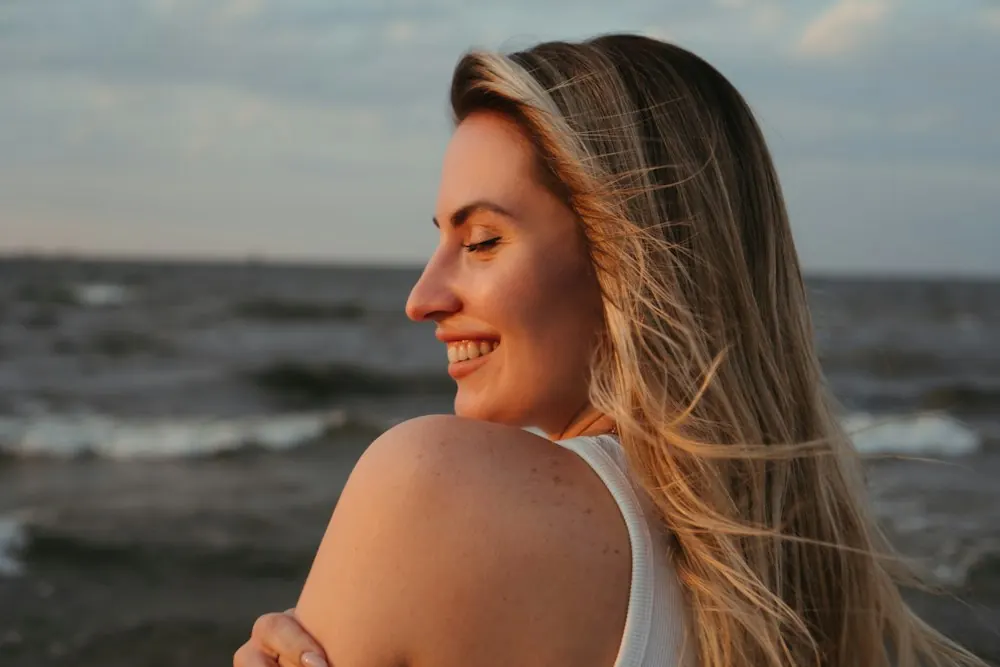 Smiling woman enjoying a sunset by the ocean